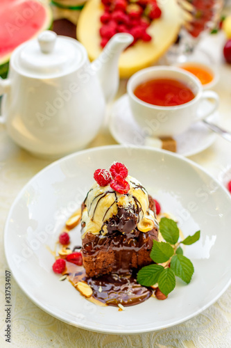 chocolate sponge cake with ice cream and fruit on a served table