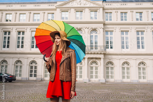 Fashionable beautiful woman with a colorful umbrella on an autumn day in a red dress in Brussels © Aleksei Zakharov