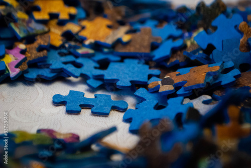 Close-up of colorful pieces of puzzle. One standing puzzle piece on the table. Stack of Puzzle Pieces. Puzzle pieces. Puzzle figures. Puzzle for fun. 