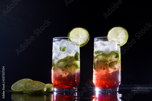 Campari drink with gin with ice and lemon on black background