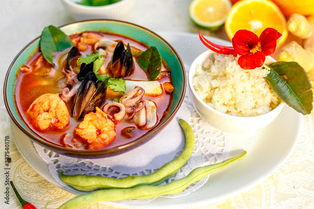 Thai soup tom yam with seafood (octopus, shrimps), herbs and vegetables served on the table with ingredients, healthy food Thai soup tom yam with seafood (octopus, shrimps), herbs and vegetables served on the table with ingredients, healthy food
