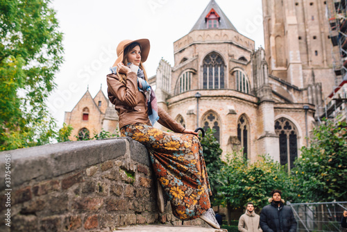 a girl sits on the Boniface bridge overlooking the Church of our lady of Vrouwekerk in Bruges