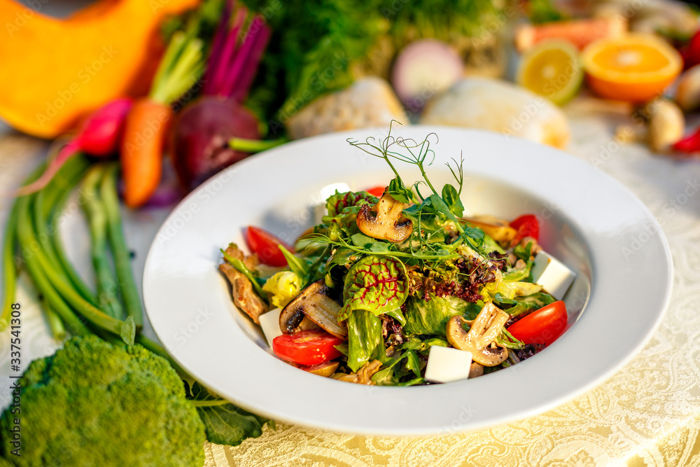 Fresh salad with mushrooms, cheese, tomatoes, herbs and vegetables served on the table with the ingredients, healthy food