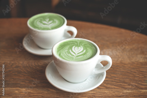 A Cup of matcha green latte with art on a table in a coffee shop