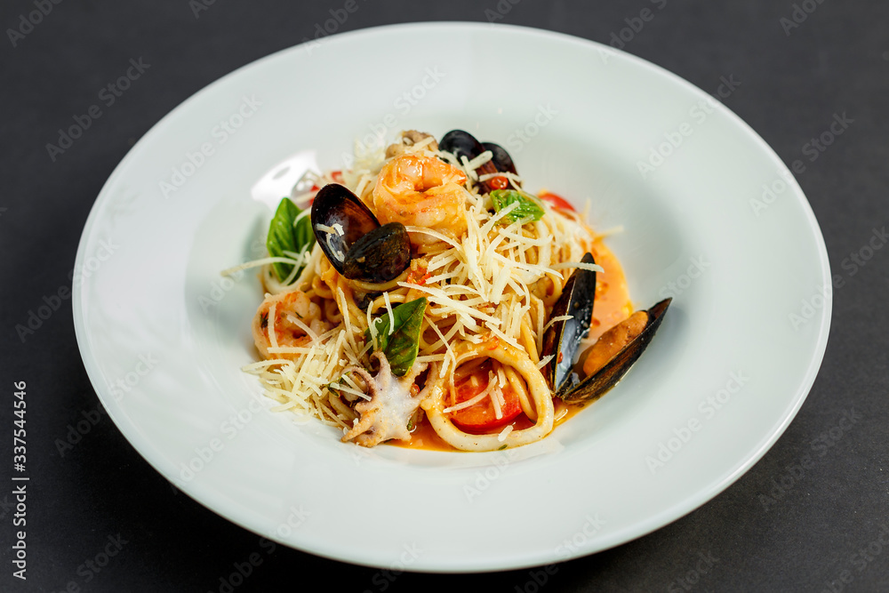delicious Italian pasta with cheese and seafood (mussels, shrimps) on a white plate, isolated