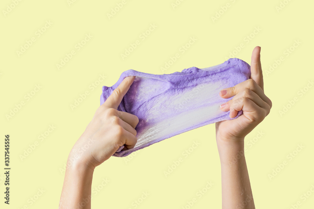 A large lilac slime stretched out by the hands of a child on a yellow background.