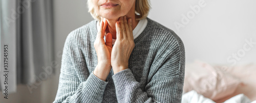 Sick senior adult elderly women touching the neck feeling unwell coughing with sore throat pain.Healthcare and medicine concept photo