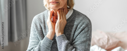 Sick senior adult elderly women touching the neck feeling unwell coughing with sore throat pain.Healthcare and medicine concept