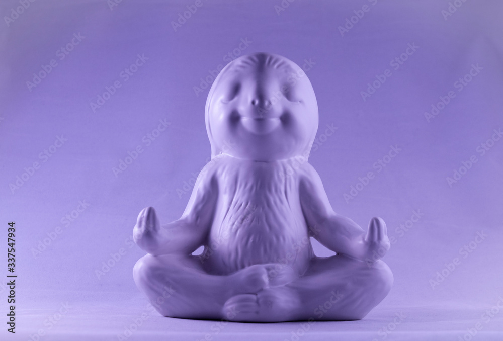 Purple smiling and calm looking sloth ornament sitting in the lotus meditating position Purple smiling and calm looking sloth ornament sitting in the lotus meditating position