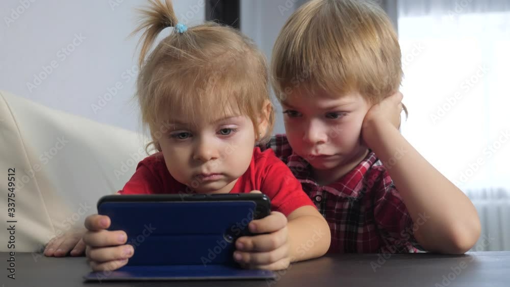 children watch online video lifestyle on a smartphone. little boy and girl brother sister watch online streaming broadcasting cartoons on the phone children watch online video lifestyle on a smartphone. little boy and girl brother sister watch online streaming broadcasting cartoons on the phone