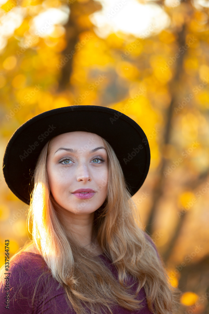 Portrait of beautiful caucasian woman with long fair hair in black hat outside on warm sunny day. Autumn nature backsides. Back to basics concept. Relaxing, calm meditation concept Portrait of beautiful caucasian woman with long fair hair in black hat outside on warm sunny day. Autumn nature backsides. Back to basics concept. Relaxing, calm meditation concept