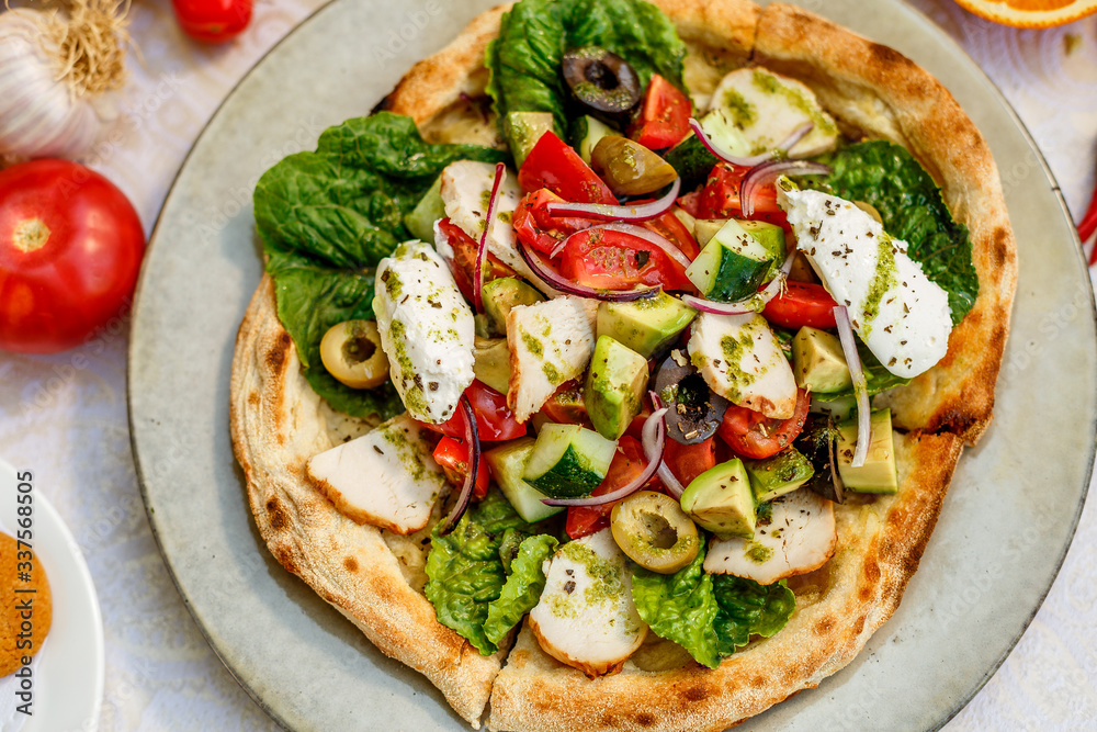salad with chicken cheese and vegetables on a flat cake on a decorated table salad with chicken cheese and vegetables on a flat cake on a decorated table