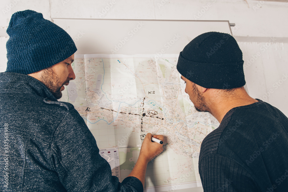 Burglars making plans for crime on city map Burglars making plans for crime on city map