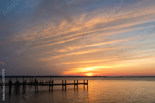 Pier Over Calm Water at Sunset with Gold and Blue Sky with Clouds
