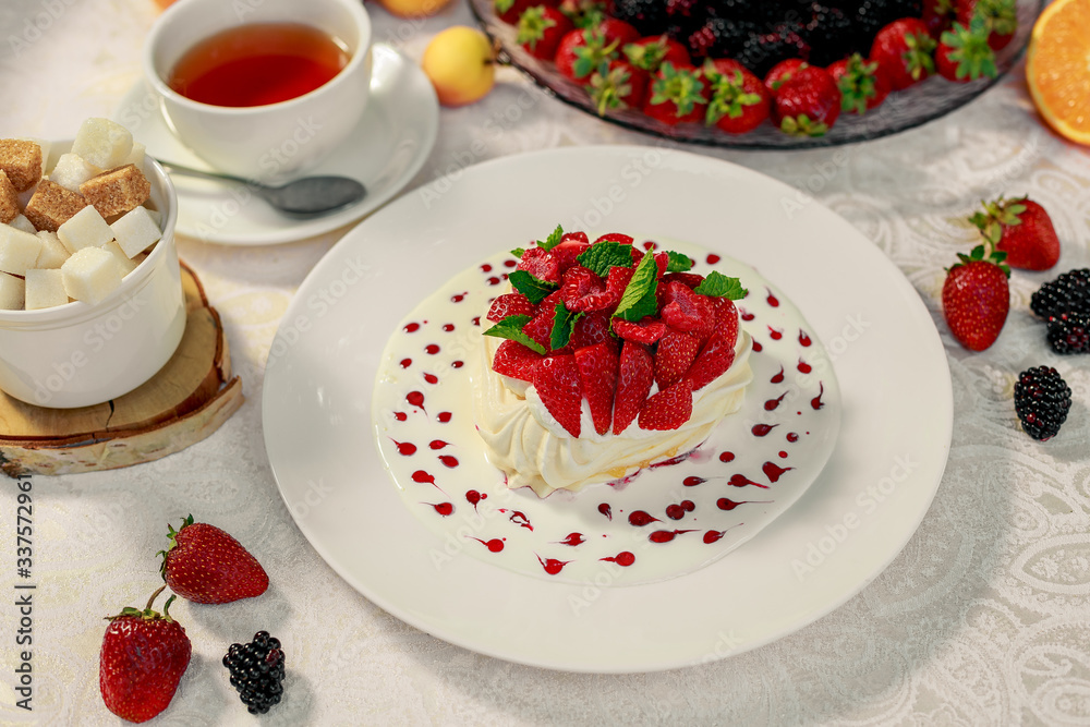 Pavlova dessert with cream mint and strawberry in a white plate on a white table Pavlova dessert with cream mint and strawberry in a white plate on a white table