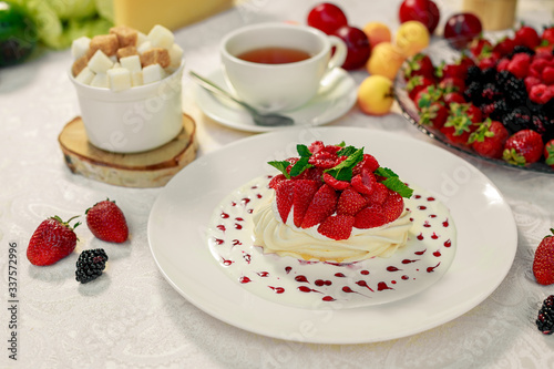 Pavlova dessert with cream mint and strawberry in a white plate on a white table