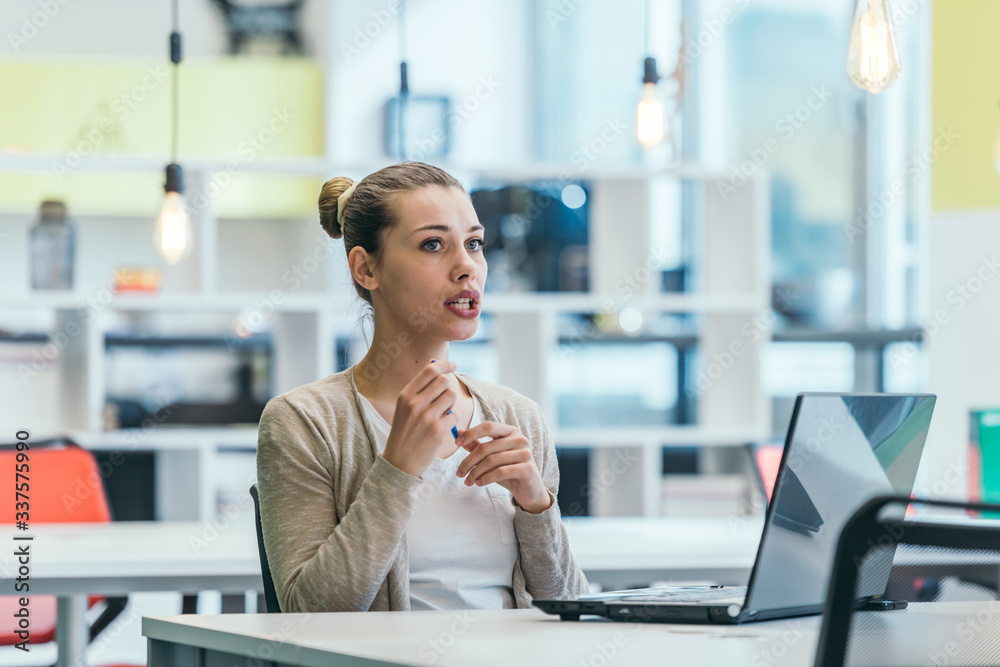 Blonde businesswoman ( employee ) working on a laptop in a modern office. Blonde businesswoman ( employee ) working on a laptop in a modern office.