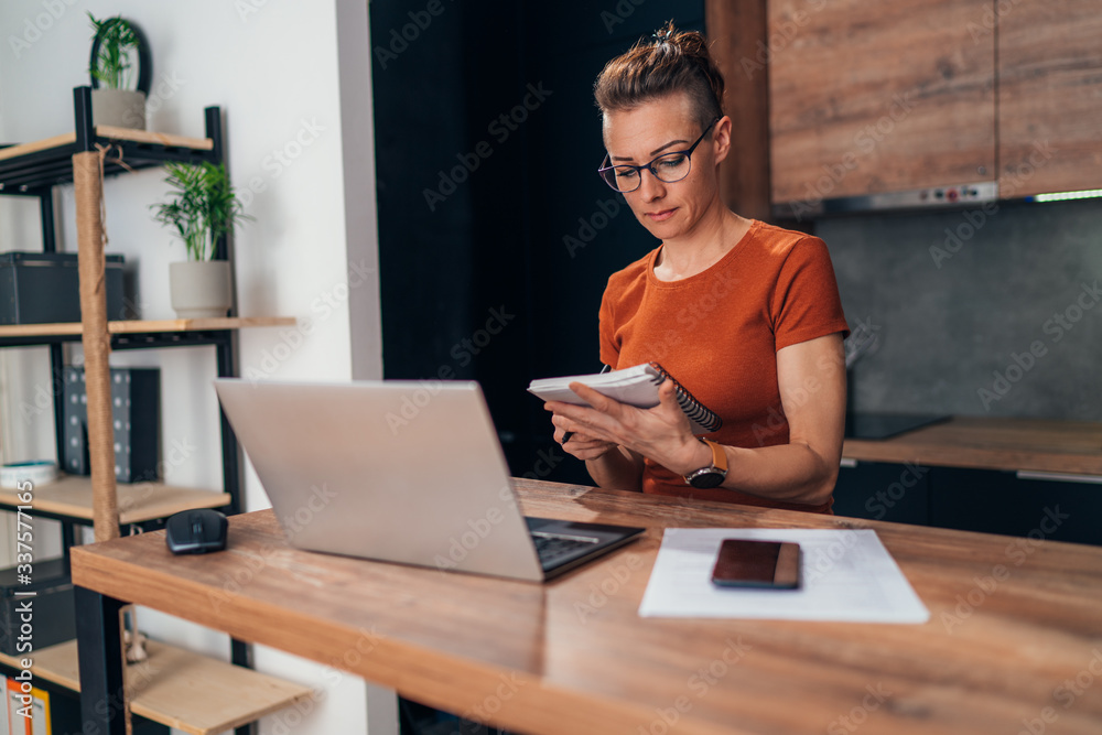Beautiful woman writing notes while working from home. Beautiful woman writing notes while working from home.
