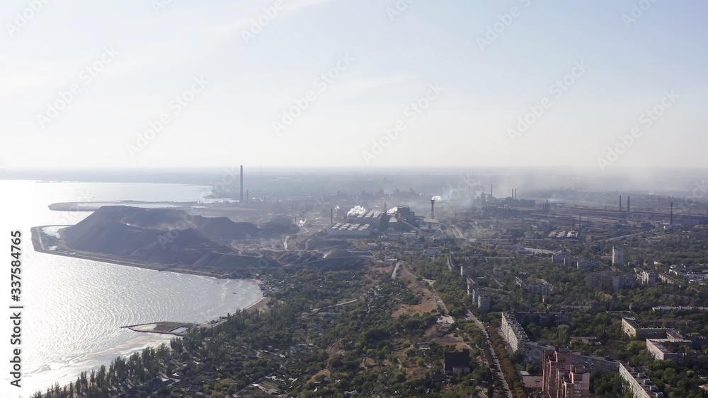 Industrial city in summer. On the horizon, a metallurgical plant near the sea. Aerial view. Mariupol, Ukraine
