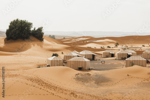 Contemporary luxury glamping camp in Morocco Sahara desert. Sand dunes around. Many white modern eco tents. photo