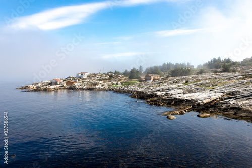 Buildings along scenic rocky coastline near Sjobadet Myklebust public swimming area, Tananger, Norway, May 2018