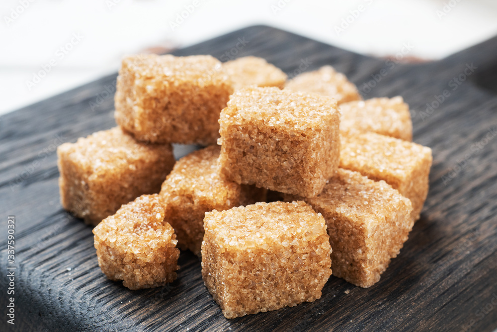 A few cubes of cane sugar on a wooden stand. Copy space. A few cubes of cane sugar on a wooden stand. Copy space.