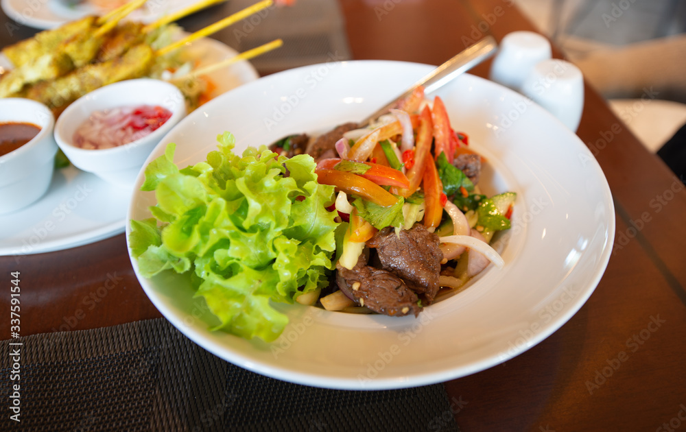 Spicy salad with meat on the dinning table and side dishes Spicy salad with meat on the dinning table and side dishes