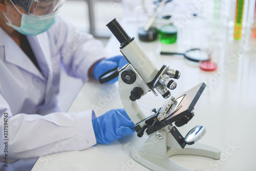 Asian old female scientist doctor using the microscope in chemical lap