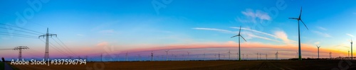 viele Windr  der bei Sonnenuntergang stehen auf einem Feld und produzieren Strom