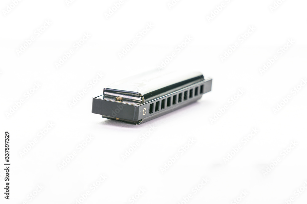 Close-up of a simple metal harmonica in C, isolated on a white background Close-up of a simple metal harmonica in C, isolated on a white background