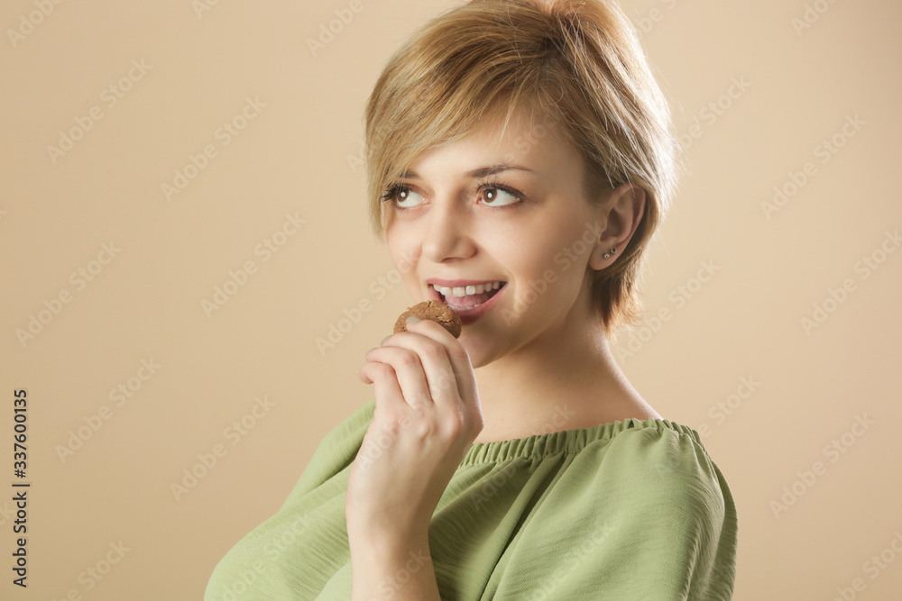 Studio shot of happy young woman eating chocolate chip cookie Studio shot of happy young woman eating chocolate chip cookie
