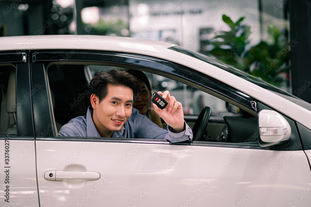 Young Asian smiling man getting keys of a new car. Concept for car rental