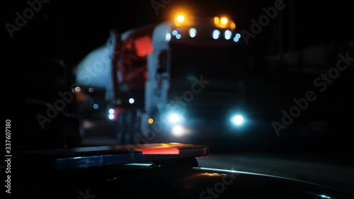 A heavy truck for transporting bulky goods against the backdrop of a police flashing light at night.