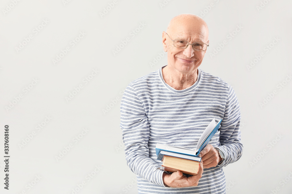 Portrait of elderly man with books on grey background Portrait of elderly man with books on grey background