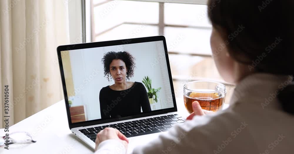 Online job interview concept. African business woman manager conferencing in app talking with female applicant, remote employee working from home office by webcam video call. Over shoulder screen view Online job interview concept. African business woman manager conferencing in app talking with female applicant, remote employee working from home office by webcam video call. Over shoulder screen view