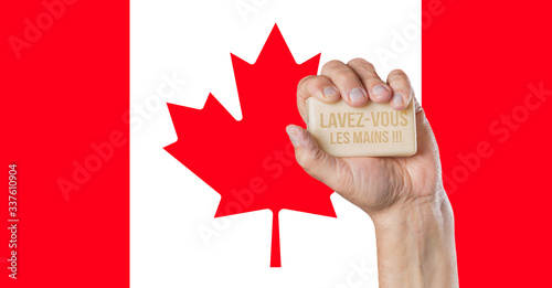 Male hand holding soap with words: Lavez-vous les mains and Canadian flag behind photo