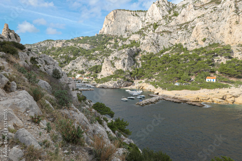 Mountains with green grass and grey rocks near the sea. Blue sky and white clouds.