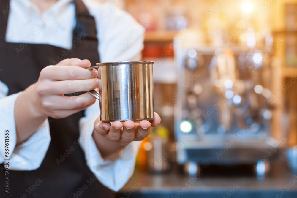 Closeup female hands are holding metal cup of aromatic coffee. Barista woman prepared, brewed espresso, americano, latte cappuccino using professional machine in cafe, restaurant. Take away, to go. Closeup female hands are holding metal cup of aromatic coffee. Barista woman prepared, brewed espresso, americano, latte cappuccino using professional machine in cafe, restaurant. Take away, to go.