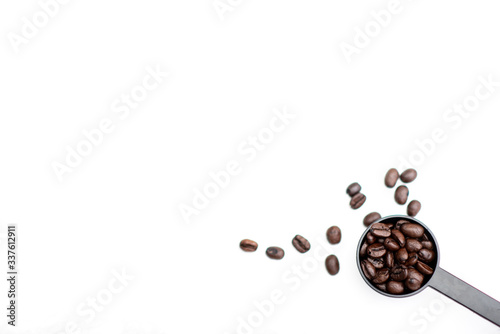 Roasted coffee beans in a coffee spoon on a white background.