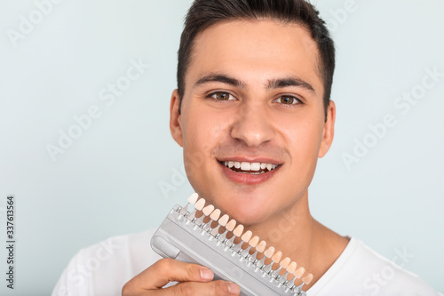 Man with teeth color samples on light background
