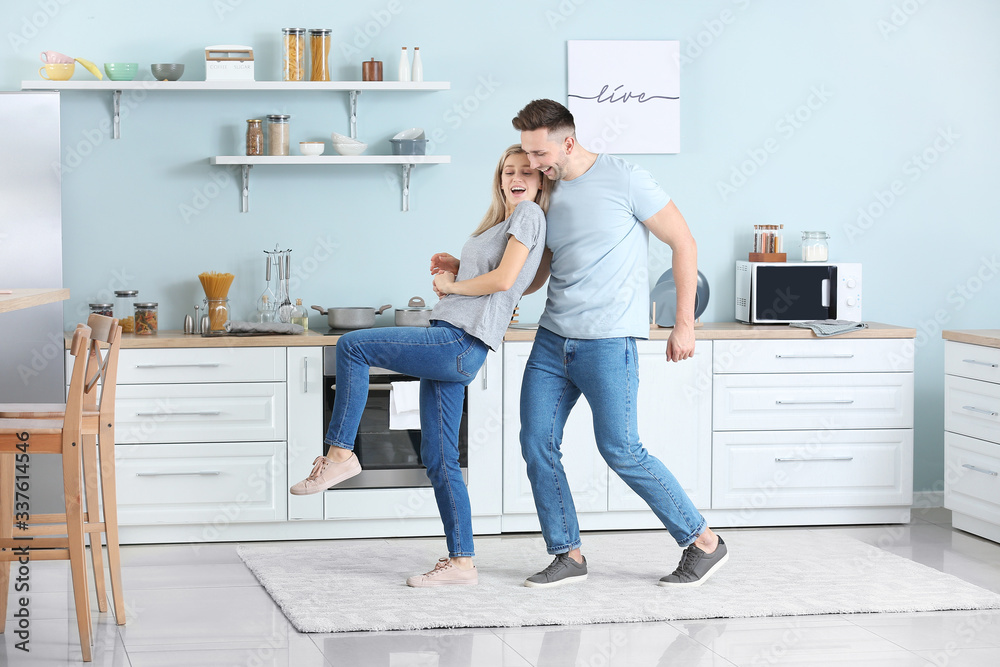 Happy dancing young couple in kitchen