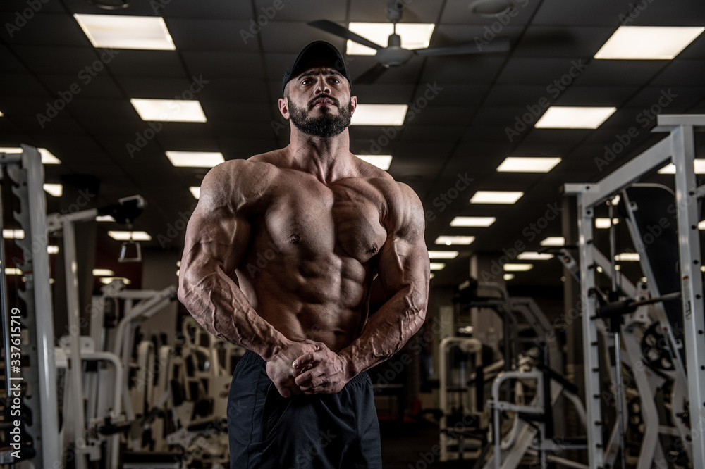 muscular male physique concept of strong athlete showing big muscles in empty gym during self isolation