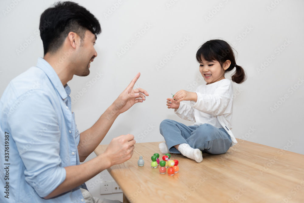 A pair of young Asian father and daughter are applying nail polish in the living room A pair of young Asian father and daughter are applying nail polish in the living room