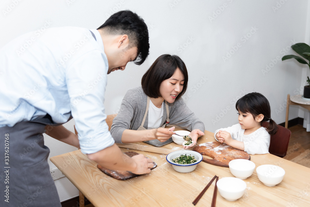 Young Asian mom and dad making dumplings with daughter Young Asian mom and dad making dumplings with daughter