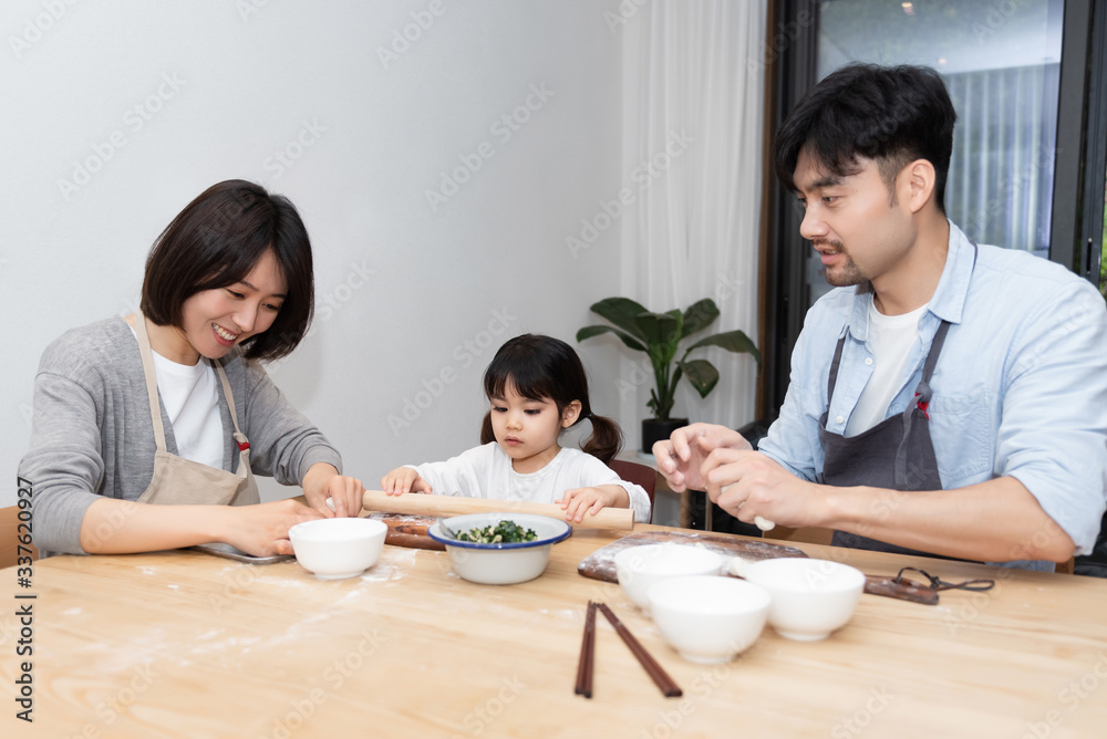 Young Asian mom and dad making dumplings with daughter Young Asian mom and dad making dumplings with daughter