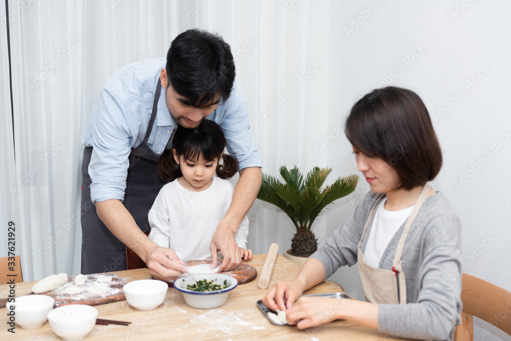 Young Asian mom and dad making dumplings with daughter Young Asian mom and dad making dumplings with daughter