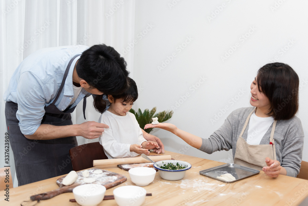 Young Asian mom and dad making dumplings with daughter Young Asian mom and dad making dumplings with daughter