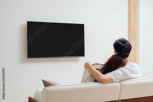 Young Asian couple at home watching TV