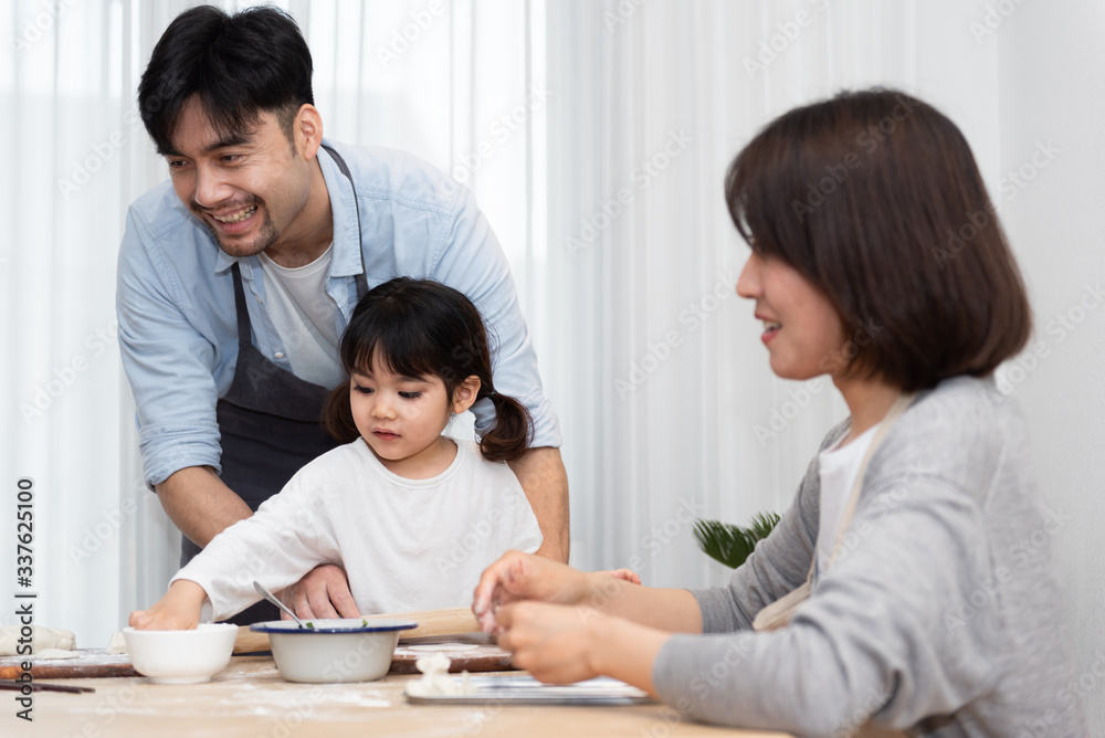 Young Asian mom and dad making dumplings with daughter Young Asian mom and dad making dumplings with daughter