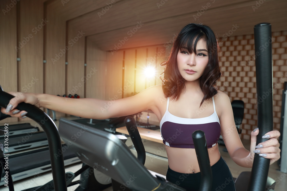 Happy and smiling young beautiful asian woman in sportswear jogging or working on exercise machine in gym. Cute and sporty girl running in fitness. (sport concept) Happy and smiling young beautiful asian woman in sportswear jogging or working on exercise machine in gym. Cute and sporty girl running in fitness. (sport concept)
